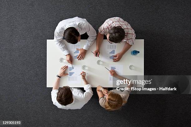 a business meeting with three businessmen and a businesswoman, overhead view - female with group of males stock pictures, royalty-free photos & images