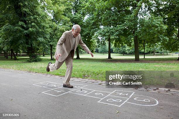 senior man playing hopscotch in the park - standing on one leg fotografías e imágenes de stock