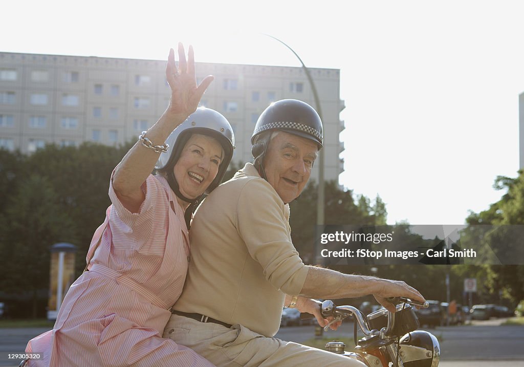 Senior couple happy on motorbike as woman waves