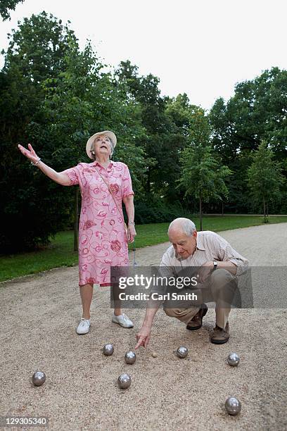 senior man and woman have dispute playing boules in the park - verkehrsweg für fußgänger stock-fotos und bilder