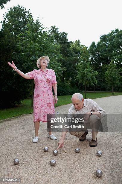 senior man and woman have dispute playing boules in the park - causal dress stock pictures, royalty-free photos & images