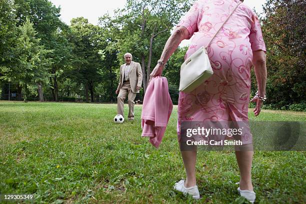senior couple play soccer in the park - senior kicking stock pictures, royalty-free photos & images