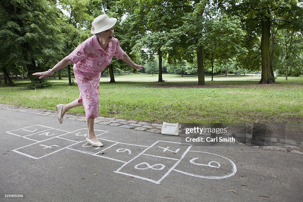 Senior woman plays hopscotch trying to keep her balance