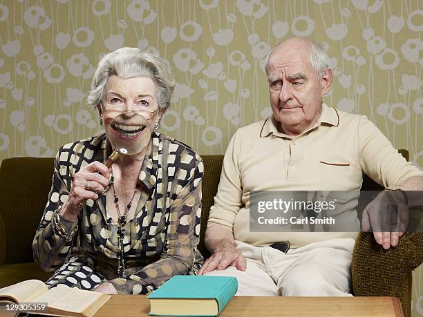 senior man frowns as senior woman magnifies appearance of her mouth with magnifying glass - tooth bonding stock pictures, royalty-free photos & images