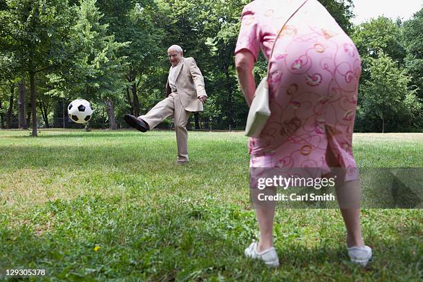 senior couple play football in the park - two guys playing soccer stockfoto's en -beelden