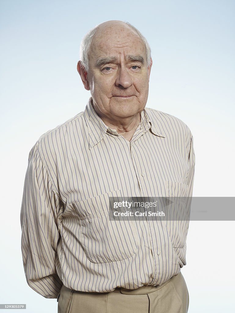 Profile of senior man with hands behind back looking at camera