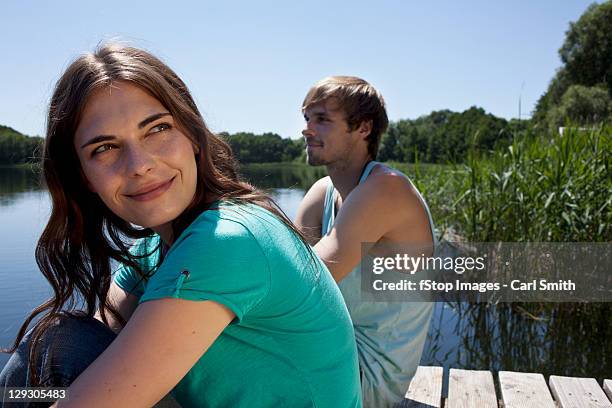 couple side by side on jetty with girl looking very happy - steg zwei menschen stock-fotos und bilder