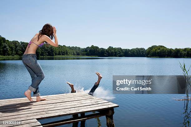 guy splashes into water from jetty as girl watches - summer press day ストックフォトと画像