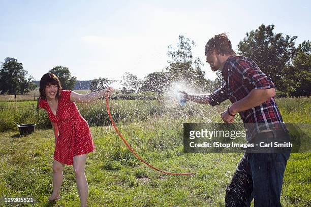 man and woman spray each other with water in field - spraying weeds stock pictures, royalty-free photos & images