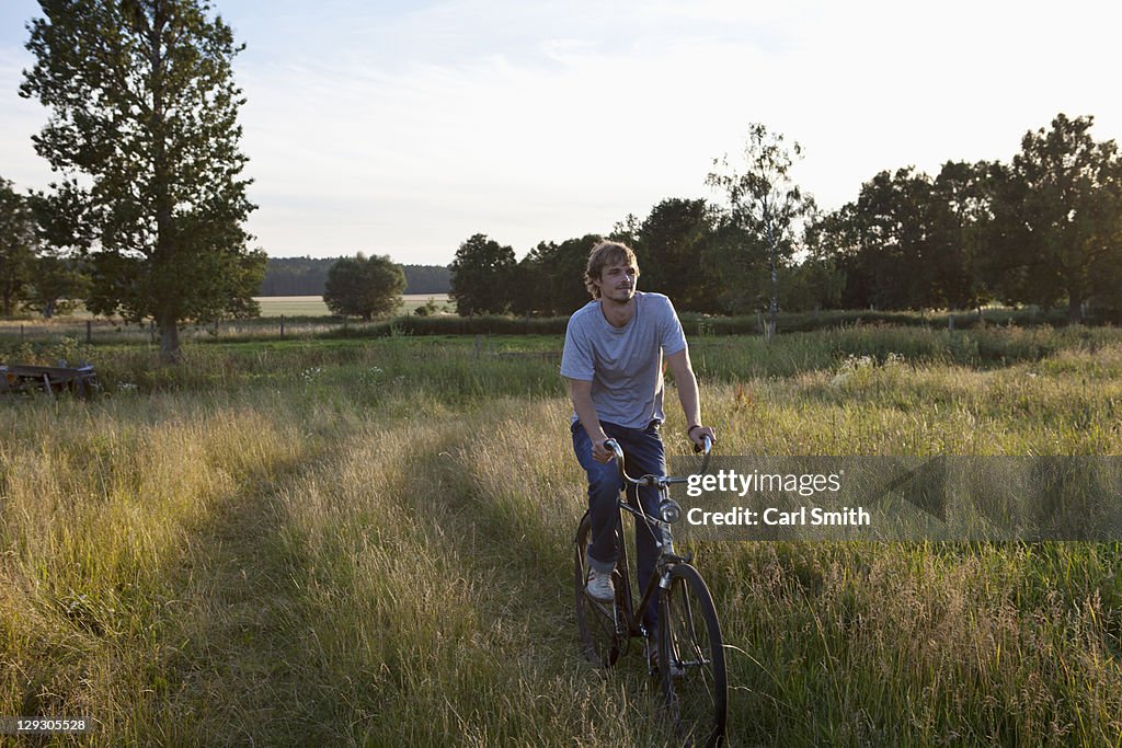 Guy cycles through secluded field on bike