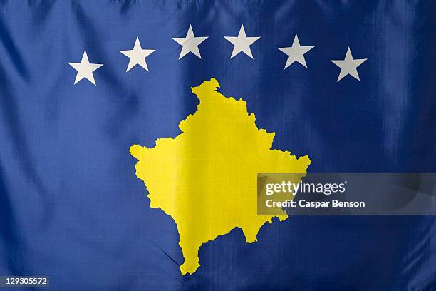 kosovo flag, blue with a gold covered map of kosovo under an arc of six white stars - kosovo stock pictures, royalty-free photos & images