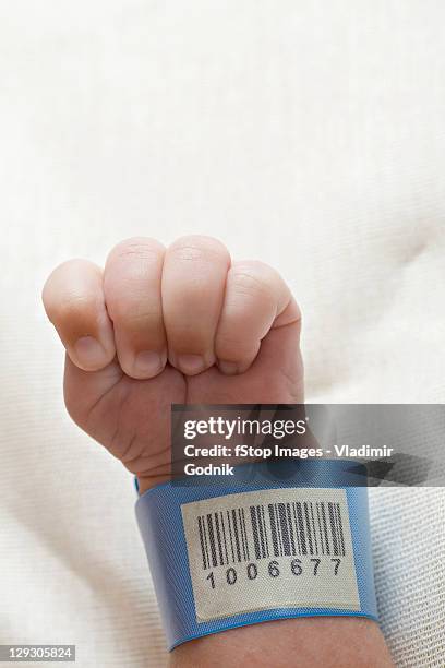 a hospital id bracelet on a baby's wrist - naamplaatje etiket stockfoto's en -beelden