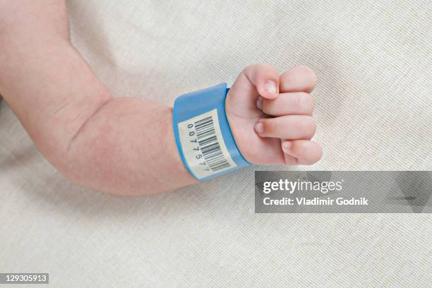 a hospital id bracelet on a baby's wrist - naamplaatje etiket stockfoto's en -beelden