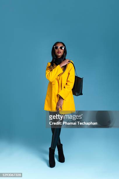fashionable woman in a yellow coat - blue purse stock pictures, royalty-free photos & images