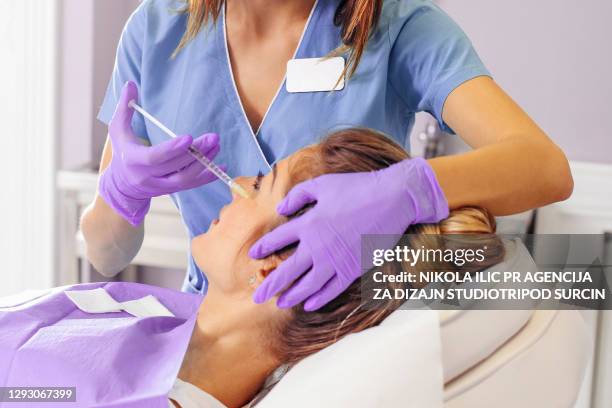 belle femme âgée d’âge moyen mûr dans le traitement à la chirurgie plastique et à la clinique faciale de correction avec le docteur féminin - correction fluid photos et images de collection