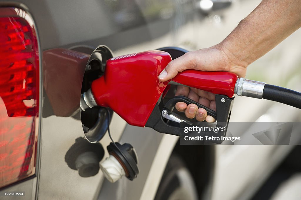 USA, New Jersey, Jersey City, Hand holding fuel pump refueling car