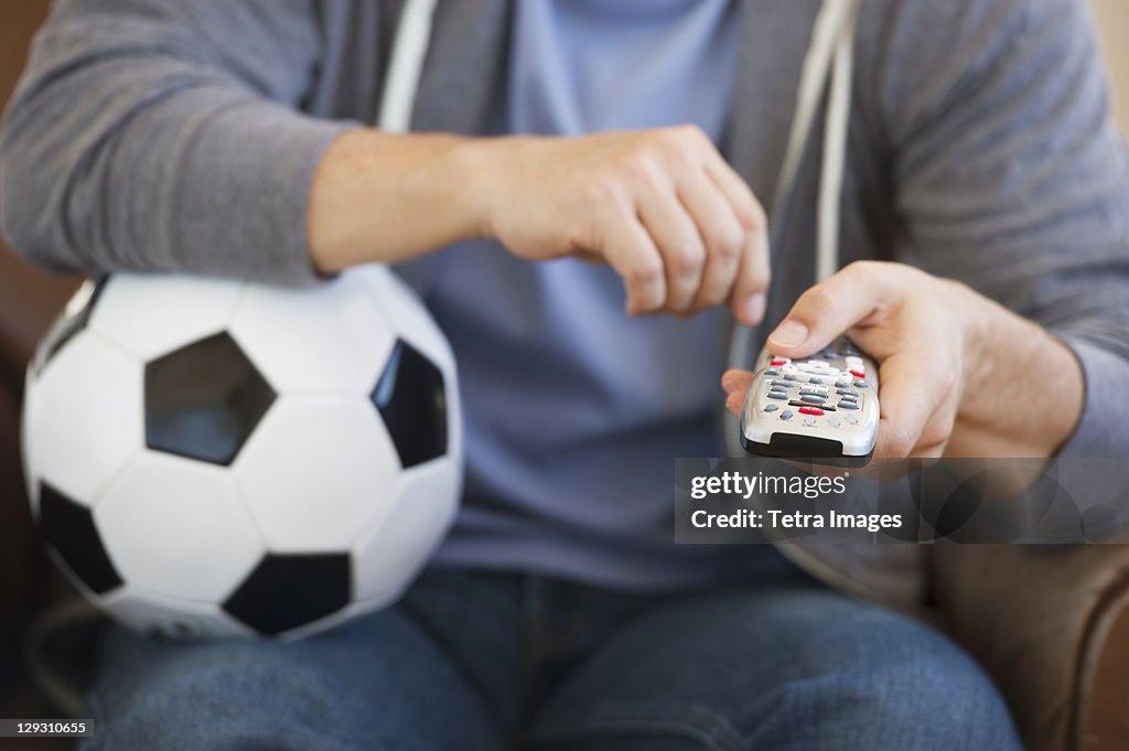 Man holding soccer ball and remote control