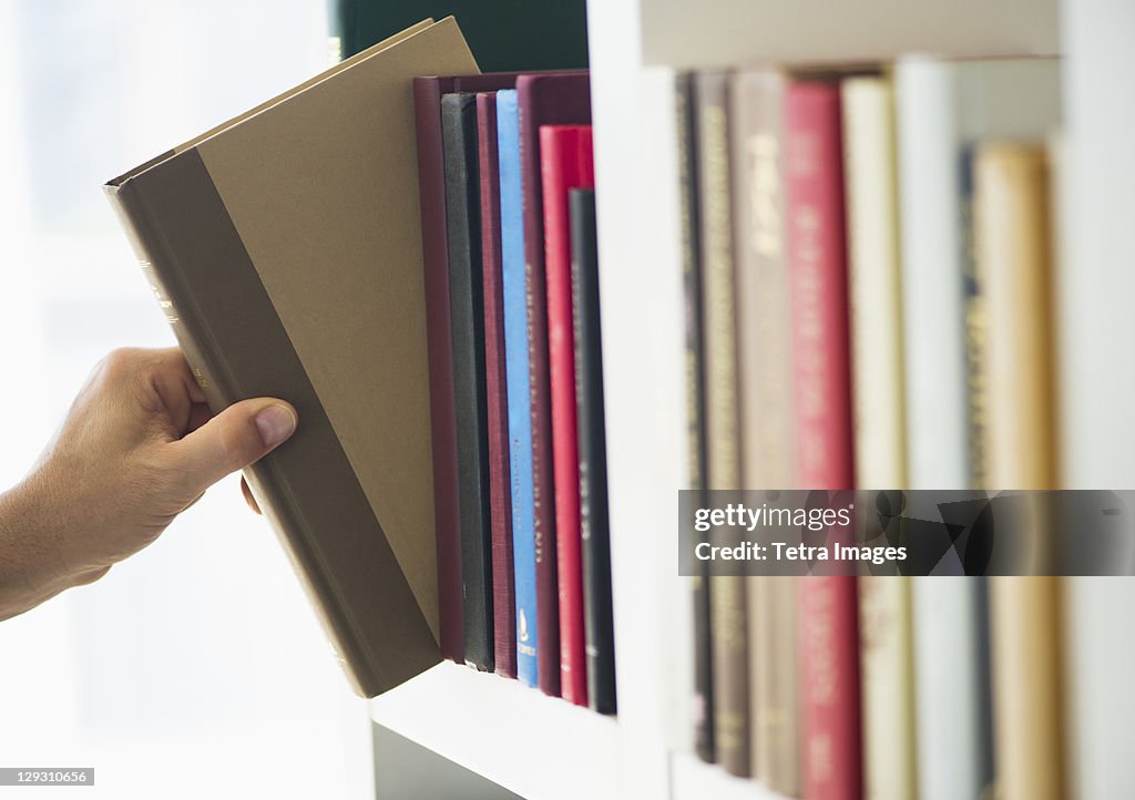 Hand choosing book from shelf