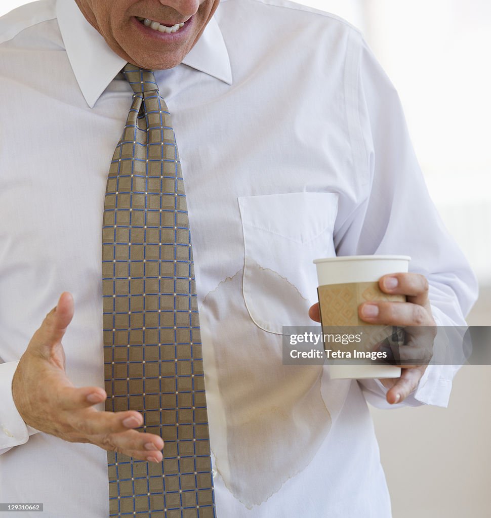 Businessman spilling coffee on shirt