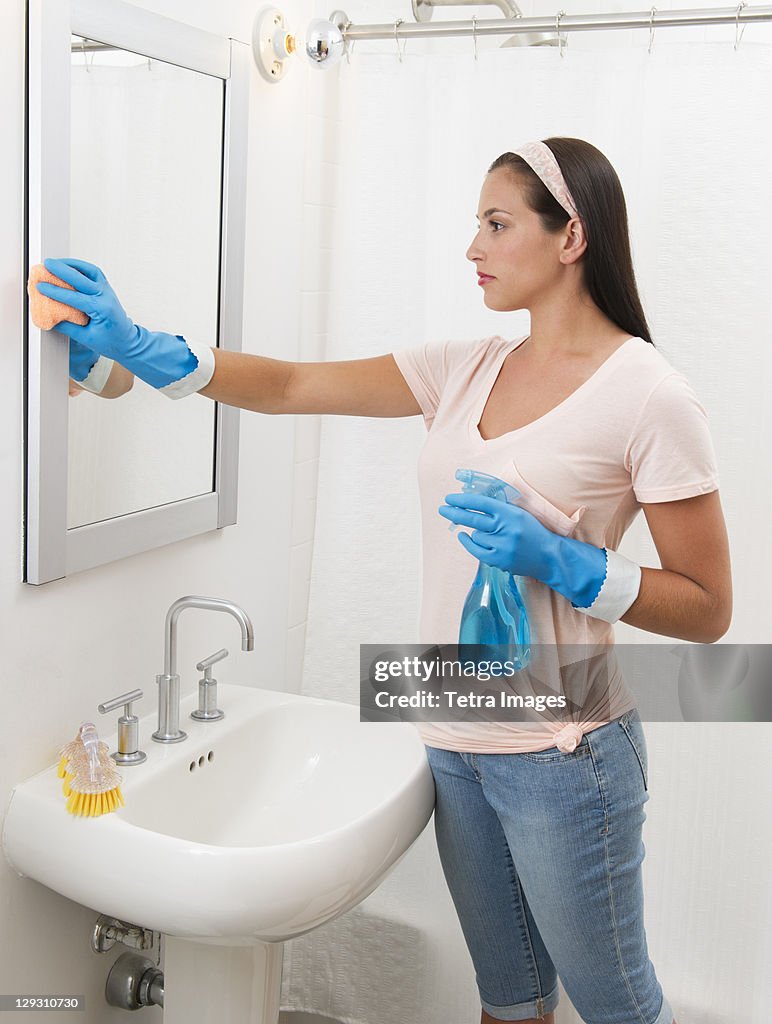 Young woman cleaning bathroom