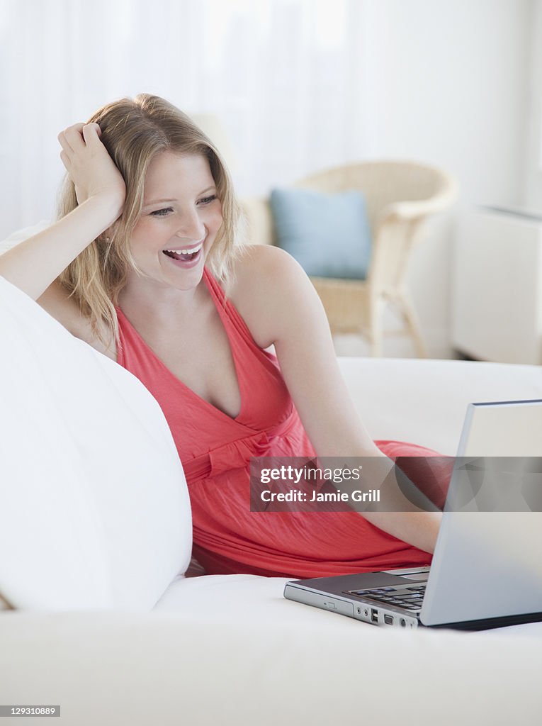 USA, New Jersey, Jersey City, Young woman with laptop on sofa