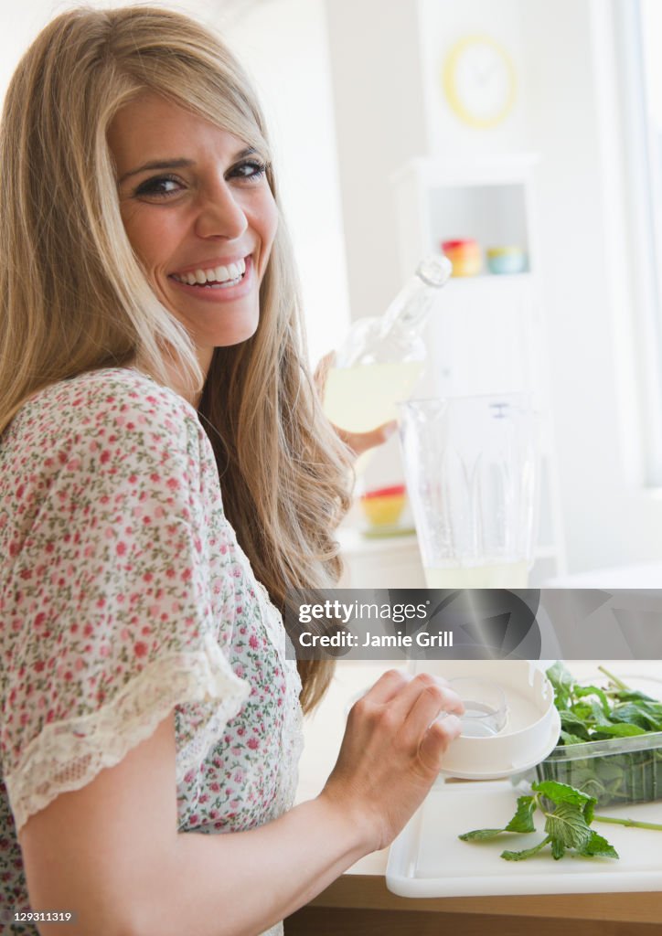 USA, New Jersey, Jersey City, Smiling woman preparing drink