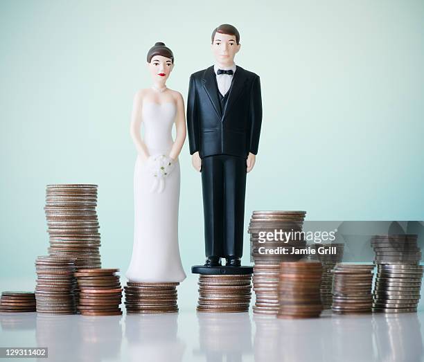 close up of wedding cake figurines on stacks of coins - bröllopstårtsfigur bildbanksfoton och bilder