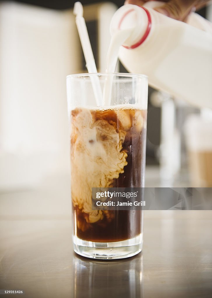 USA, New Jersey, Jersey City, Close up of hand pouring milk into iced coffee