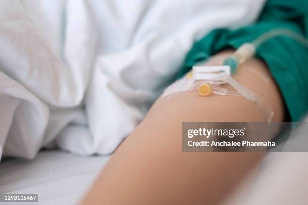 medical concept: patients saline in the hospital, young lady's hand with medical drip intravenous needle, give salt water on hospital bed. intravenous therapy is a therapy that delivers fluids directly into vein. - iv going into an arm 個照片及圖片檔
