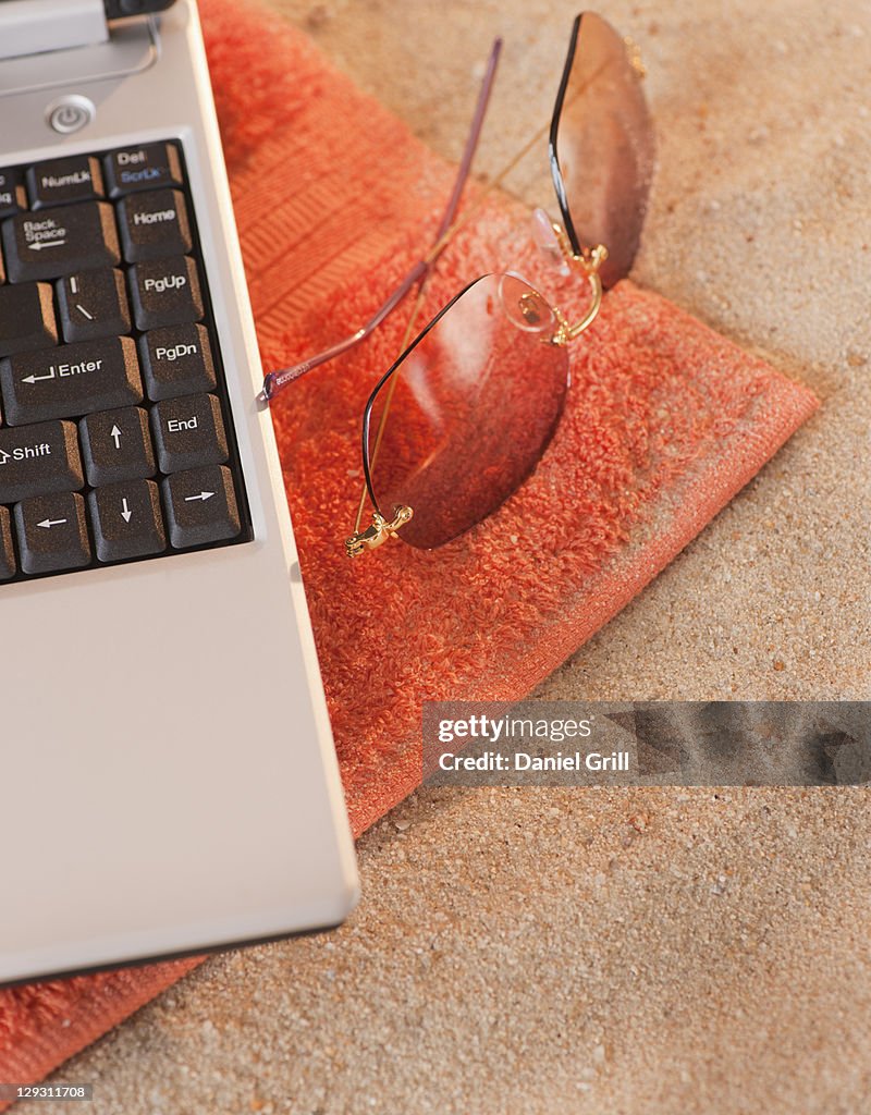 Close up of sunglasses and laptop on towel