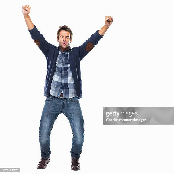 studio shot of young man celebrating with arms raised - cheering stock-fotos und bilder