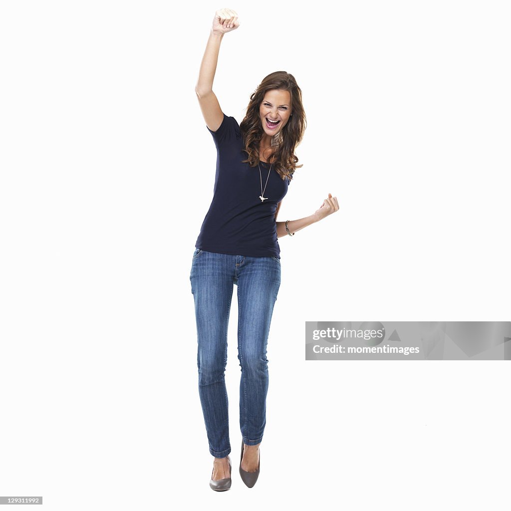 Studio shot of young woman celebrating with arm raised