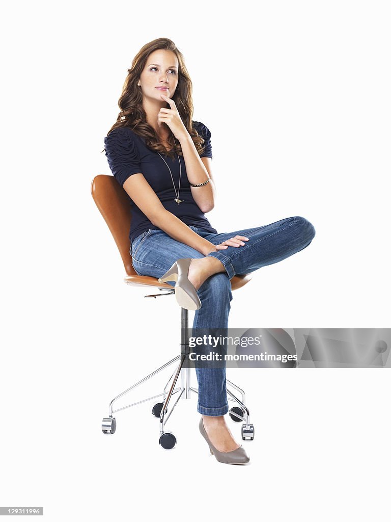 Studio shot of young woman sitting on chair and thinking