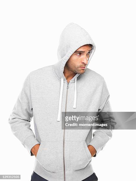 young man in hoodie standing with hands in pockets - uomo incappucciato foto e immagini stock