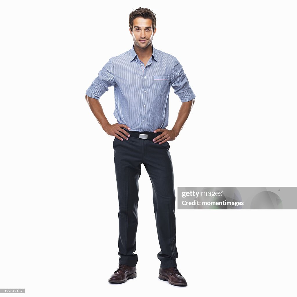 Portrait of young business man standing with hands on hips and smiling against white background