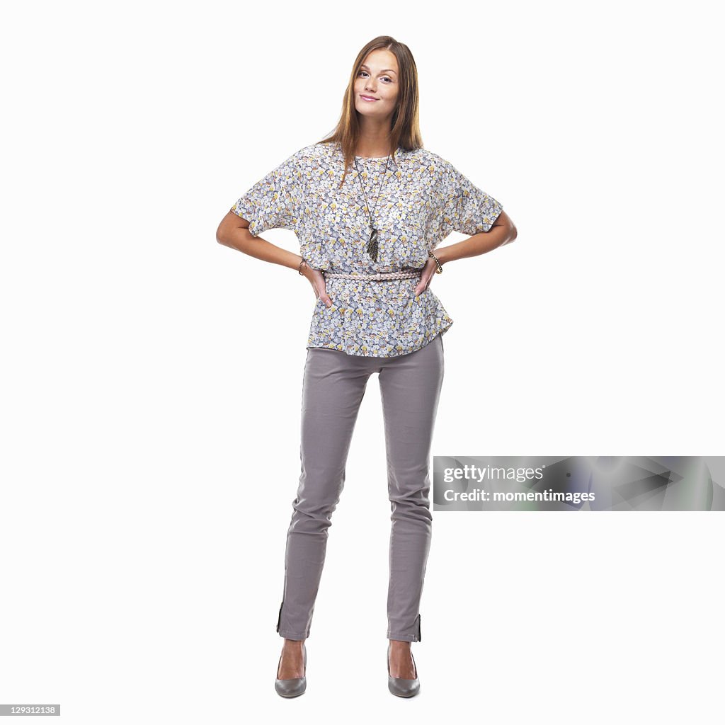 Beautiful smiling woman standing with hands on hips against white background