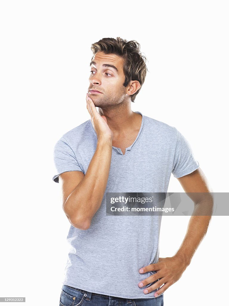 Studio shot of thoughtful young man with hand on chin