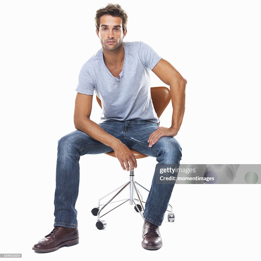 Studio shot of smart young man sitting on chair