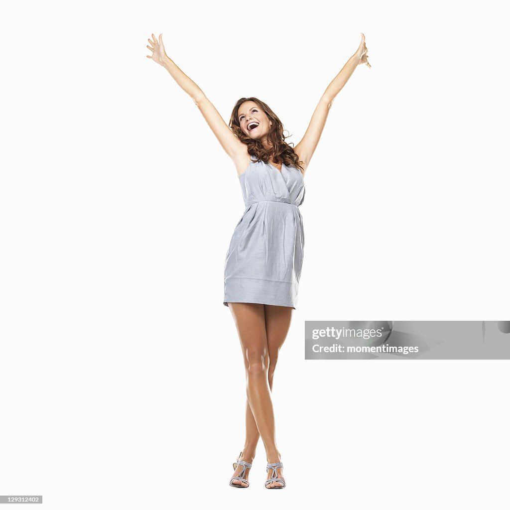 Studio shot of young excited woman celebrating success with hands raised