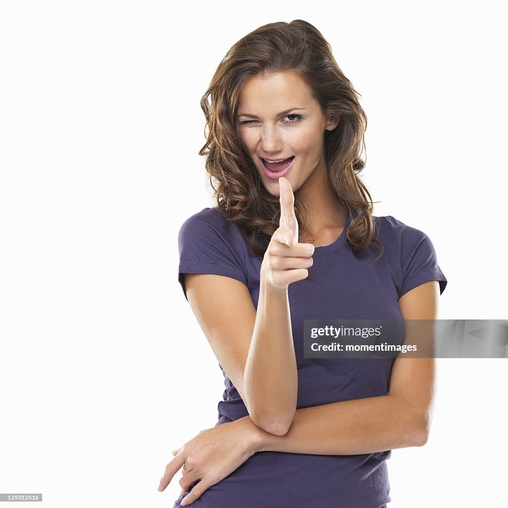 Studio portrait of woman pointing at camera and winking