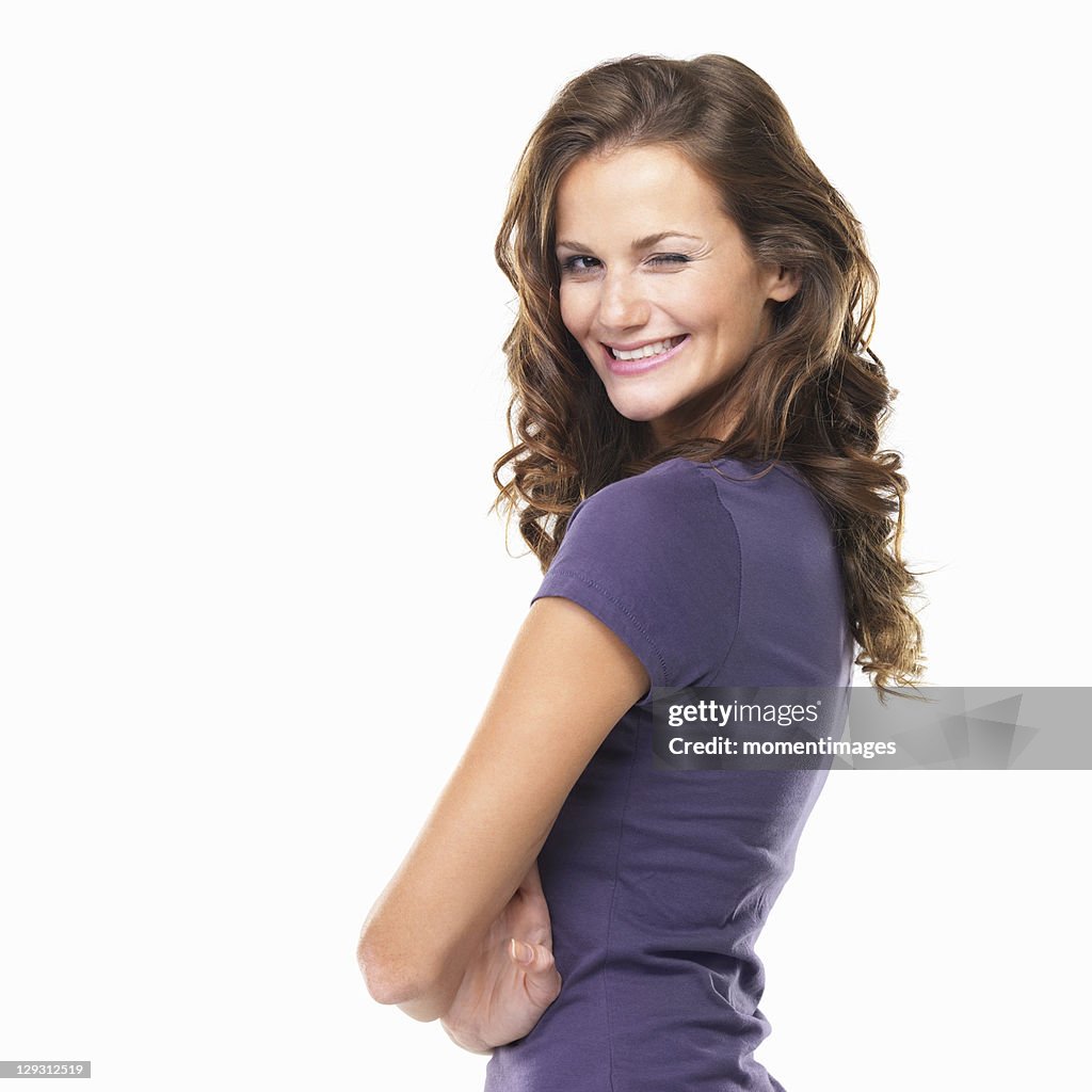 Studio portrait of cute young woman winking and smiling
