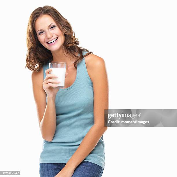 studio portrait of attractive young woman smiling and holding glass of milk - people drinking stock pictures, royalty-free photos & images