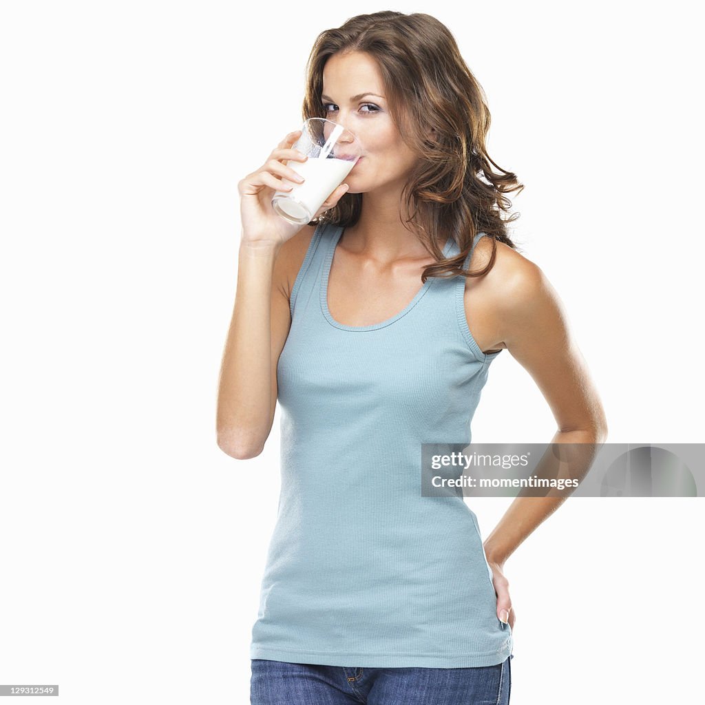 Studio shot of attractive young woman drinking milk