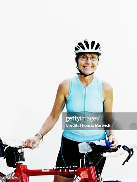senior female triathlete standing holding bicycle - bike white background stockfoto's en -beelden