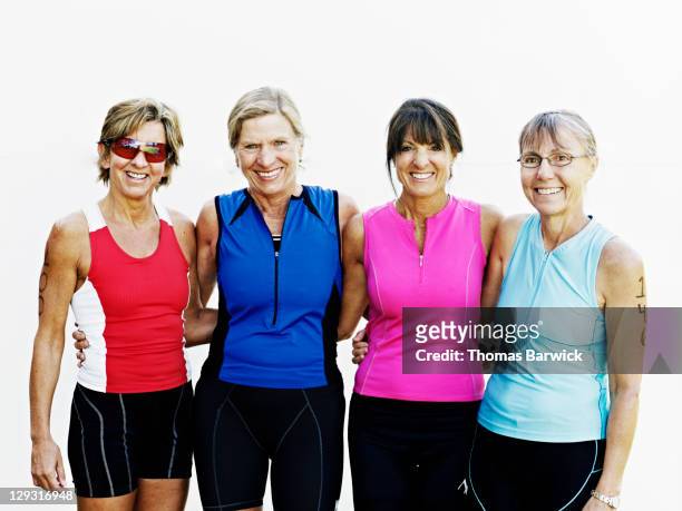 Group of four female triathletes standing smiling