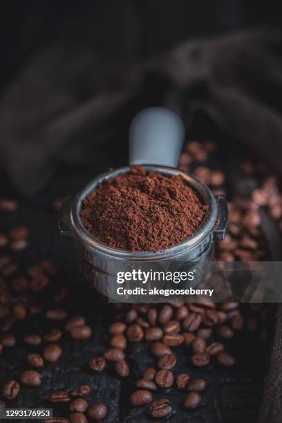 tamped puck of coffee grounds within basket of portafilter and coffee beans - coffee powder stock-fotos und bilder