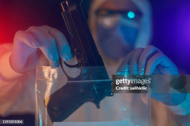 a male forensic scientist adding 9mm pistol evidence into evidence bag - coroner stock pictures, royalty-free photos & images