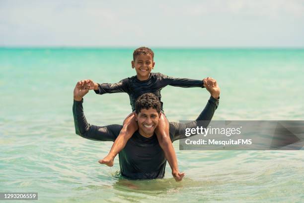 father putting son on his shoulders on the beach - alagoas stock pictures, royalty-free photos & images