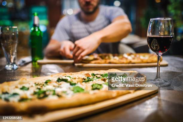 close up photo of an italian pizza and a glass of red wine in a restaurant. eating in a restaurant / going out concept. - italian food and wine stock pictures, royalty-free photos & images