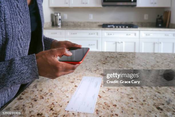 woman deposits check electronically with smart phone - cheque deposit stock pictures, royalty-free photos & images